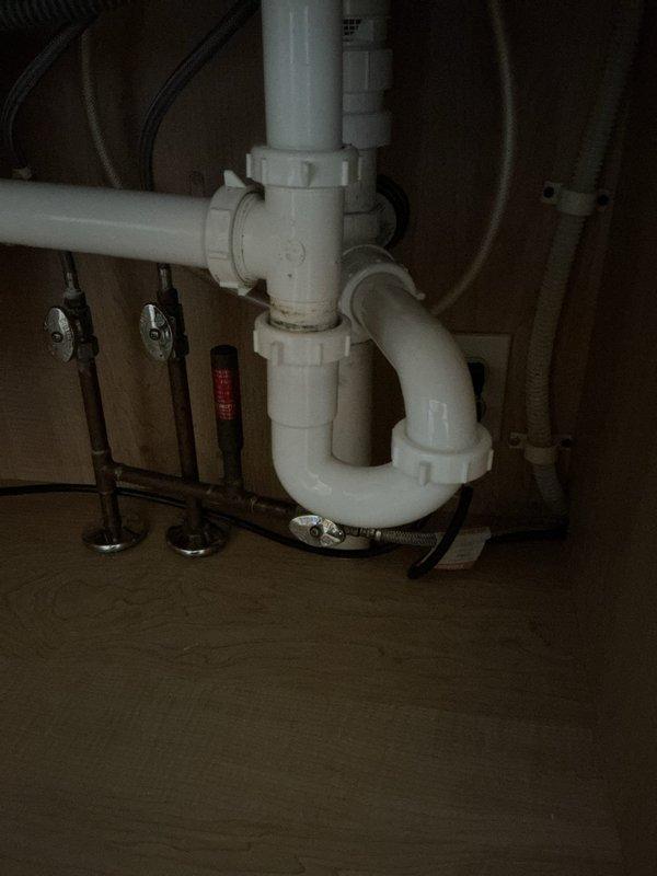 Completed removal and replacement of deteriorated galvanized kitchen drain line section in basement area. Accessed existing plumbing system beneath kitchen sink, disconnected old galvanized piping, and installed new PVC drain assembly with proper P-trap configuration to ensure code-compliant drainage and prevent sewer gas infiltration. Work performed in unfinished basement utility area near laundry machines, with all connections tested and verified leak-free upon completion.