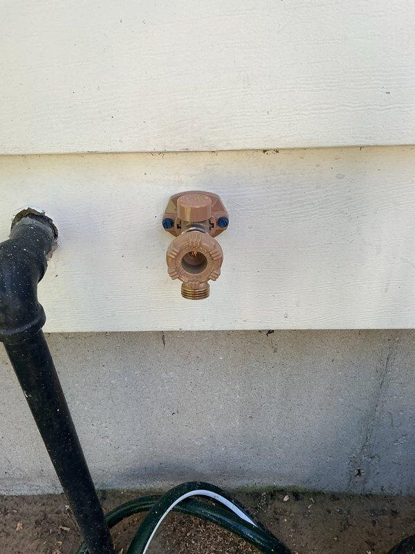 Replaced exterior hose bib mounted on wooden siding with new frost-free sillcock assembly, including copper valve body and proper wall mounting hardware. Installed water hammer arrestor fitting with secure clamp assembly to prevent pressure surges and extend fixture lifespan.