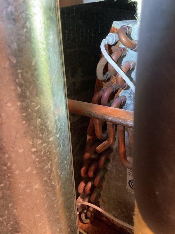 Responded to no-cooling complaint on 20-year-old residential air conditioning unit. Upon arrival, found evaporator coil completely frozen with ice buildup, preventing proper heat exchange and airflow. Connected manifold gauge set to measure system pressures and diagnosed low refrigerant charge as primary cause of freezing condition. System was operating below normal suction pressure, causing evaporator temperature to drop below freezing point. Added refrigerant to bring system pressures within manufacturer specifications. Monitored system operation to ensure proper defrost of coil and return to normal cooling function. Unit restored to operational status with adequate cooling capacity.