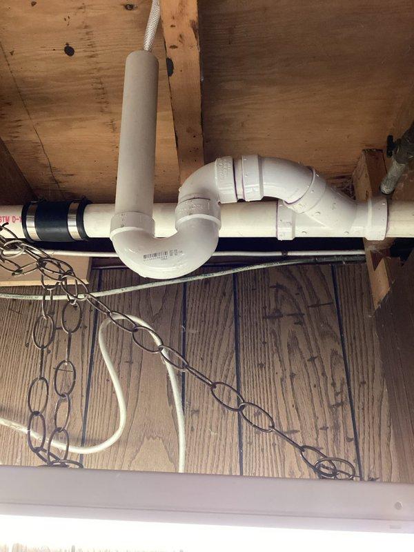 Responded to backup issue with newly installed AC condensate drain line. Removed and cleaned clogged PVC drain fittings that were causing water to back up into the system. Reinstalled proper drainage assembly with P-trap configuration in basement area to ensure adequate flow and prevent future blockages.