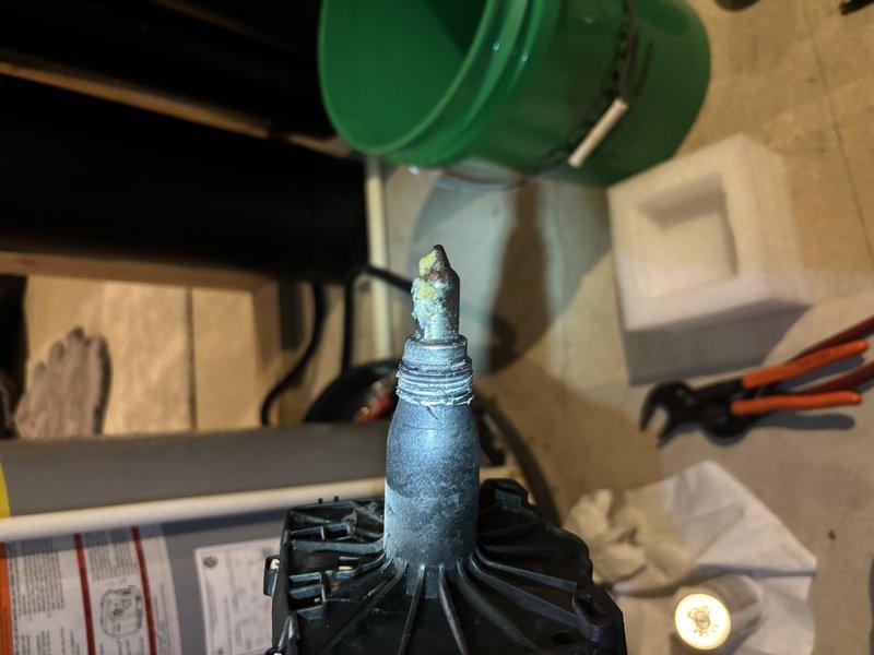 Responded to service call for gas valve issue affecting entire home over several months in four-year-old residence. Upon inspection, discovered severely corroded compressor terminal with heavy white and blue-green crystalline oxidation buildup obscuring original metal finish. Collected water sample from system showing murky brownish-tan discoloration, indicating potential moisture intrusion contributing to electrical component degradation. Documented corrosion damage to terminal post and surrounding wire connections on black plastic base. Photographed affected components and water contamination for service records.