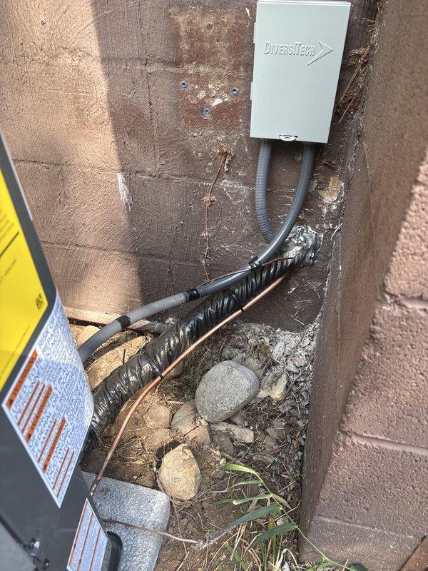 # A/C Replacement Installation

Completed full air conditioning system replacement including outdoor condensing unit and indoor air handler. Installed new DiversiTech disconnect box with proper electrical conduit routing along exterior wall. Mounted outdoor unit on pad with appropriate clearances from structure. Connected refrigerant lines using copper tubing with proper insulation and secured all penetrations through building envelope. Installed required electrical disconnect with safety labeling per code requirements. Completed indoor air handler installation in basement utility area with new flexible ductwork connections to existing distribution system. Ran condensate drainage lines and electrical supply conduit to equipment. Verified proper refrigerant charge, tested system operation, and confirmed adequate airflow. All installations meet manufacturer specifications and local building codes. System tested and operational upon completion.