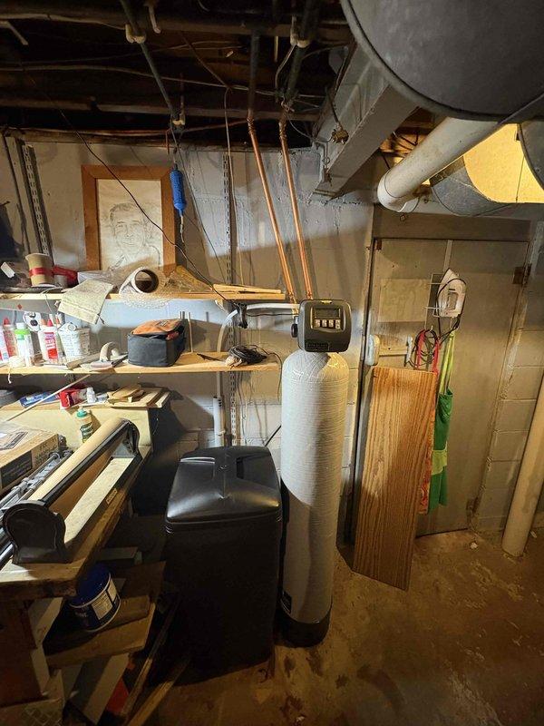 Completed water softener installation in basement utility area. Installed new cylindrical water softener unit with digital control head and connected copper supply lines to existing plumbing system. Unit is fully operational and programmed for optimal performance.