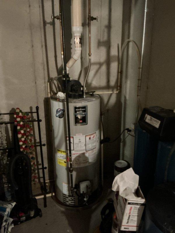 Responded to service call for water heater leak and potential furnace area water leak. Upon inspection, identified active leak from water heater connections in utility room. Examined all plumbing connections, copper supply lines, shut-off valves, and PVC drainage system. Assessed water heater condition and surrounding mechanical systems including water softener installation. Inspected furnace area for reported moisture concerns and traced potential leak sources. Documented equipment conditions and leak locations with photographs for service records. Water heater appears to be approximately 5 years old based on initial service request information.