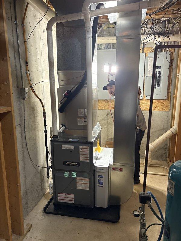 Successfully completed installation of new furnace and tankless water heater system in residential mechanical space. Mounted Energy Star certified tankless water heater unit to wall framing with complete copper piping connections including multiple supply and return lines with appropriate shut-off valves. Installed furnace system with vertical air handler assembly and connected metallic ductwork for proper air distribution throughout the home. Integrated existing water treatment equipment including pressure expansion tank and water softener system into new plumbing configuration. All copper piping routed systematically with proper spacing for maintenance access. Electrical connections completed with appropriate panel integration. System installed on proper base platform with all components positioned for optimal performance and serviceability. Installation verified operational and ready for use.