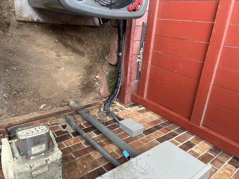 Completed full AC replacement installation at residential property. Removed existing air conditioning system and installed new American Standard condenser unit on concrete pad against exterior brick wall. Ran new refrigerant line set with proper insulation from outdoor unit to interior air handler. Installed electrical disconnect, verified proper power supply connections to existing meter panel, and ensured all electrical conduits met code requirements. Leveled and secured outdoor unit, tested system operation, verified proper refrigerant charge, and confirmed all components functioning within manufacturer specifications.