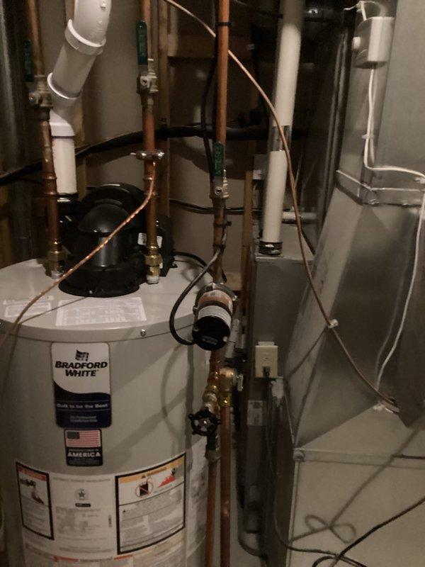 Conducted comprehensive on-site evaluation of existing residential water treatment system and plumbing infrastructure in basement utility area. Assessed current Bradford White water heater installation with copper piping connections, brass fittings, and associated circulation pump. Inspected existing blue water treatment tank and pressure tank system mounted to concrete block wall, including PVC supply lines, valve assemblies, and flexible connecting hoses. Performed visual examination of all copper and PVC piping configurations, mounting hardware, and electrical connections throughout the utility space. Documented current equipment conditions and system layout through photographic documentation. Provided professional recommendations for water treatment equipment options and discussed water testing procedures to address homeowner's water quality concerns.