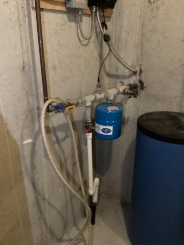 Conducted comprehensive on-site evaluation of existing residential water treatment system and plumbing infrastructure in basement utility area. Assessed current Bradford White water heater installation with copper piping connections, brass fittings, and associated circulation pump. Inspected existing blue water treatment tank and pressure tank system mounted to concrete block wall, including PVC supply lines, valve assemblies, and flexible connecting hoses. Performed visual examination of all copper and PVC piping configurations, mounting hardware, and electrical connections throughout the utility space. Documented current equipment conditions and system layout through photographic documentation. Provided professional recommendations for water treatment equipment options and discussed water testing procedures to address homeowner's water quality concerns.