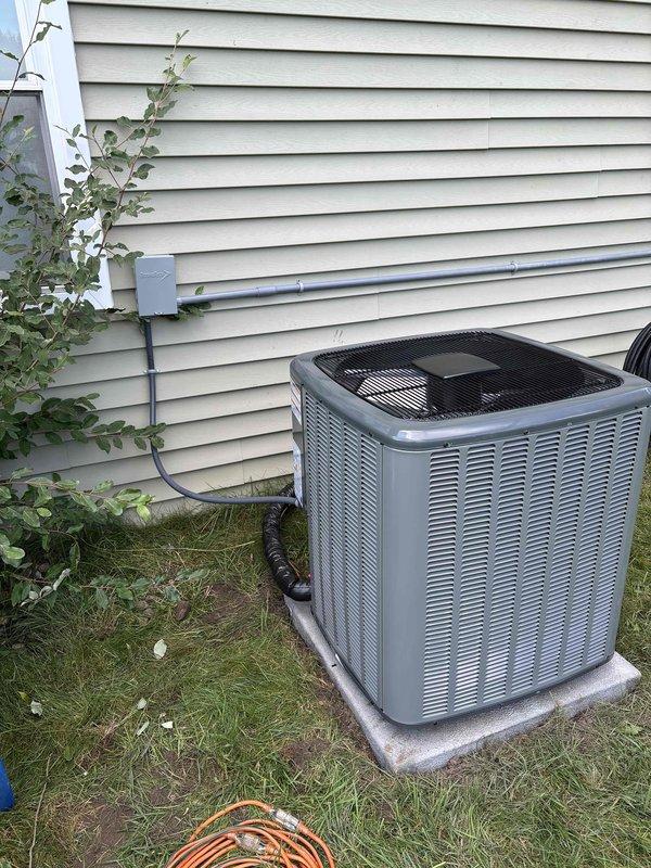 Completed full HVAC system replacement including indoor furnace unit and outdoor condensing unit. Installed new furnace in basement utility area with proper ventilation using white PVC piping, including elbows and drainage connections. Mounted unit on gray plenum base with all safety labels and specifications clearly visible. Routed black refrigerant lines from indoor unit to outdoor condenser. Installed new outdoor AC condensing unit on concrete pad with proper clearances, connected via gray PVC electrical conduit to wall-mounted disconnect box. Verified all electrical connections, refrigerant line sets, and drainage systems functioning properly. System tested and operational upon completion.