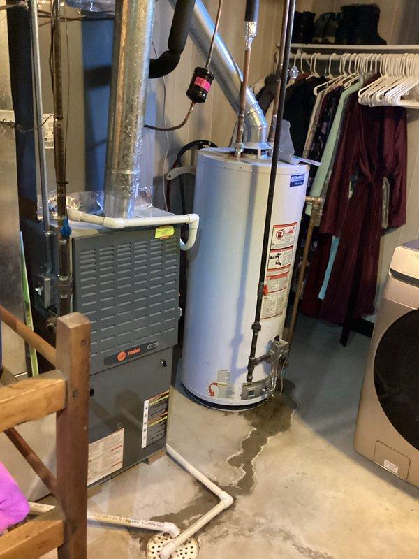 Provided estimate for water heater replacement after identifying active leak at base of existing unit, with visible water staining on concrete floor around equipment. Assessed current setup including connections to HVAC system, documented existing plumbing configuration with copper supply lines and PVC venting, and discussed options for new unit installation including extended warranty coverage.