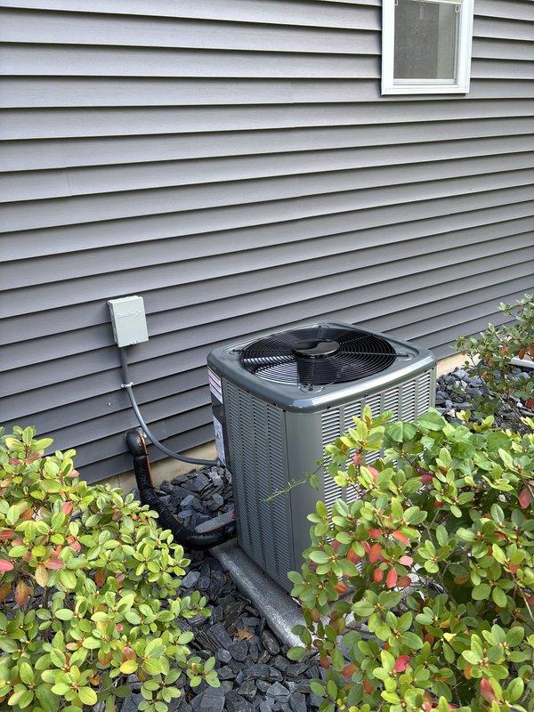 Completed full HVAC system installation including new furnace and air conditioning unit. Installed dark gray condensing unit on exterior pad with proper electrical disconnect and refrigerant line connections, positioned against home exterior with appropriate clearances and landscaping considerations. In basement, installed new furnace on protective pad with PVC intake and exhaust venting, connected air handler with metal and flexible ductwork integration to existing system. All equipment properly mounted, vented, and connected per manufacturer specifications with appropriate clearances maintained throughout installation.