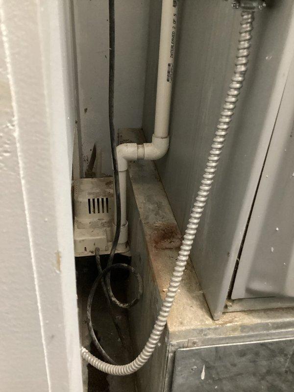 Completed annual cooling maintenance on residential AC system. Performed standard tune-up procedures including inspection of condensate pump installation and drainage system in confined mechanical space, verified proper operation of all accessible components, and documented equipment condition with photos showing PVC condensate lines, flexible conduit, and pump assembly functioning normally with minor age-related surface wear present.