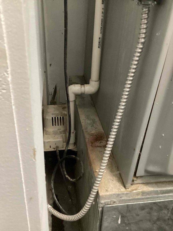 Completed annual cooling maintenance on residential AC system. Performed standard tune-up procedures including inspection of condensate pump installation and drainage system in confined mechanical space, verified proper operation of all accessible components, and documented equipment condition with photos showing PVC condensate lines, flexible conduit, and pump assembly functioning normally with minor age-related surface wear present.