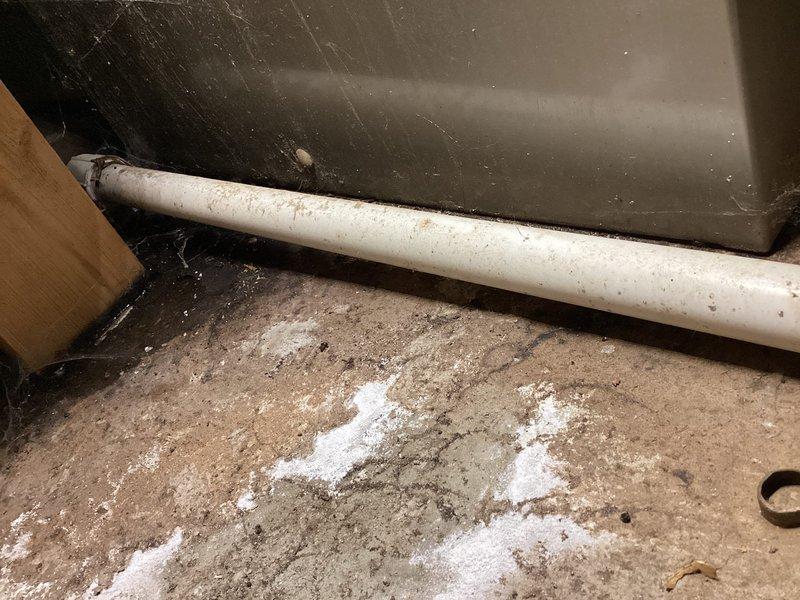 Completed annual cooling maintenance on 31-year-old Amana air conditioning system. Performed comprehensive tune-up including system inspection, cleaning, and operational testing. Documented crawlspace conditions showing PVC condensate drain line with accumulated dirt and debris on concrete floor surface, along with evidence of moisture accumulation in utility area beneath unit.