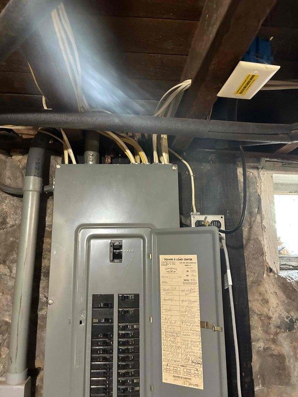 Completed estimate for central air conditioning installation in home currently equipped with boiler heating system. Property has existing ductwork previously installed, which was documented and assessed for compatibility with proposed AC system. Also evaluated feasibility of adding forced air gas furnace to work in conjunction with or replace existing boiler system. Photographed electrical panel installation in basement utility area to assess current electrical capacity and determine requirements for AC equipment, including inspection of breaker panel configuration, available circuits, and conduit routing for potential HVAC electrical connections.