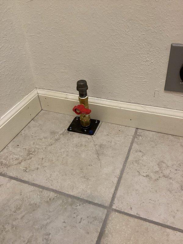 Installed new gas line for dryer from basement to laundry area on main floor. Gas valve with red shutoff handle mounted at floor level with black mounting plate, copper supply line run through ceiling joists and connected to existing gas distribution system in basement.