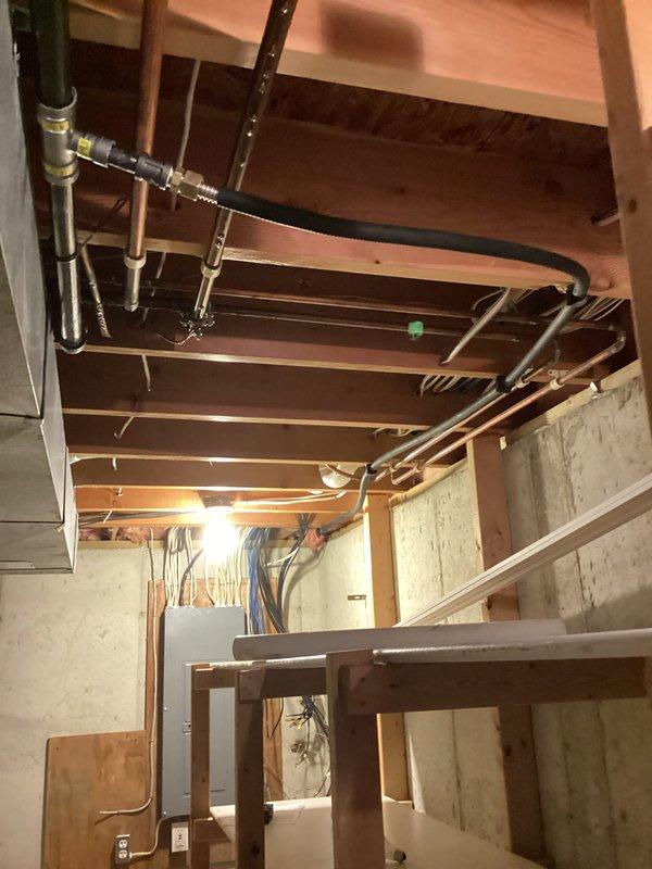 Installed new gas line for dryer from basement to laundry area on main floor. Gas valve with red shutoff handle mounted at floor level with black mounting plate, copper supply line run through ceiling joists and connected to existing gas distribution system in basement.
