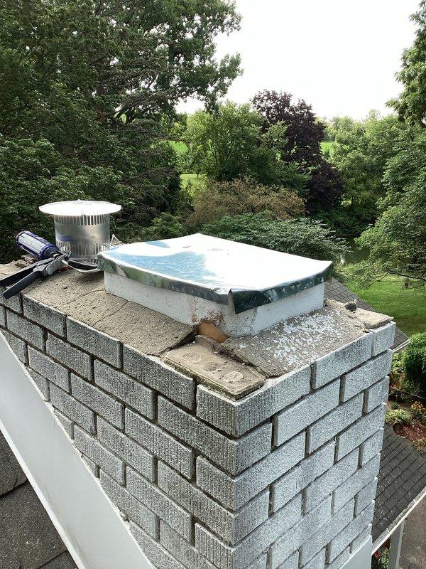 Completed follow-up chimney cleanup work following previous water heater installation. Removed construction debris and excess materials from chimney structure, ensuring all mortar remnants and brick fragments were cleared from the rooftop area. Relocated leftover materials and supplies to designated storage location behind the garage per customer request.