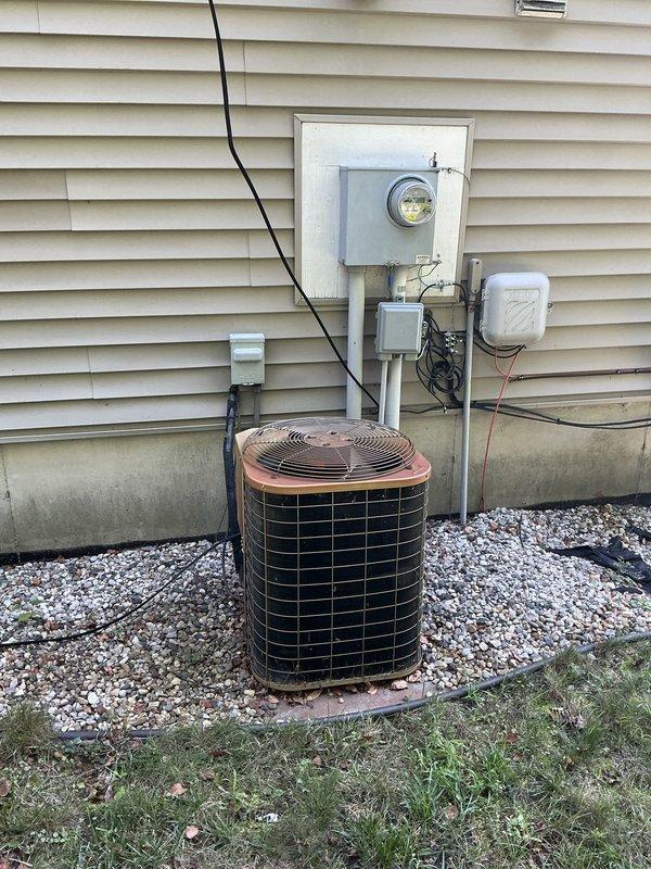 Conducted comprehensive estimate for air conditioning system and humidifier installation at residential property. Evaluated existing outdoor condenser unit with copper-colored top positioned on concrete pad with electrical connections to exterior meter, and inspected indoor beige air handler in basement with associated refrigerant lines, PVC condensate drainage, and electrical components. Documented system configuration and noted floor staining near indoor unit indicating previous moisture concerns requiring attention during proposed installation.