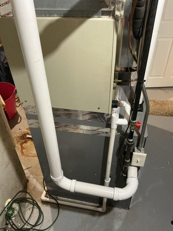 Conducted comprehensive estimate for air conditioning system and humidifier installation at residential property. Evaluated existing outdoor condenser unit with copper-colored top positioned on concrete pad with electrical connections to exterior meter, and inspected indoor beige air handler in basement with associated refrigerant lines, PVC condensate drainage, and electrical components. Documented system configuration and noted floor staining near indoor unit indicating previous moisture concerns requiring attention during proposed installation.
