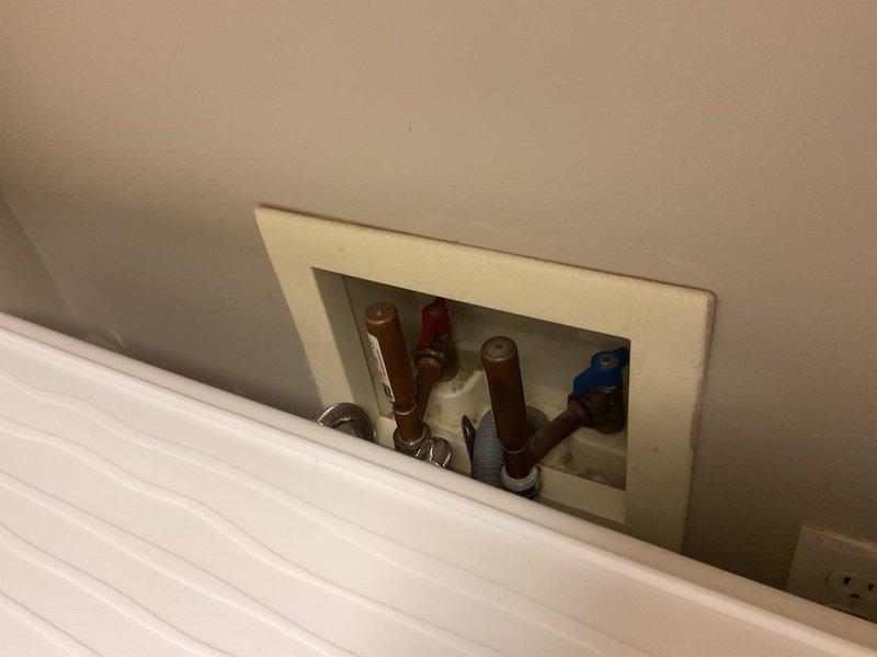 Responded to sump pump service call and completed full sump pump replacement per approval. Unit was successfully installed and tested for proper operation. Photographed completed installation showing laundry room area and plumbing access panel with visible water supply lines and valve assembly, confirming all connections are secure and system is functioning as designed.