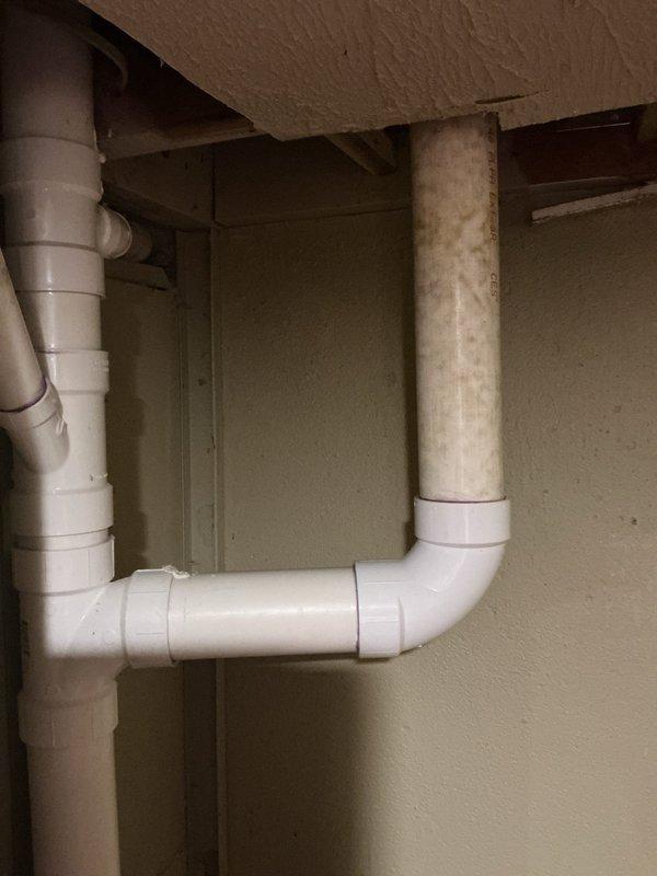 Completed quoted plumbing repair involving installation of new PVC drainage piping in basement utility area and replacement of toilet flange assembly. Installed white PVC pipe configuration with vertical and horizontal sections using appropriate elbow fittings, ensuring proper drainage slope and secure mounting. Replaced closet flange with new unit including wax ring seal to restore proper toilet connection point.