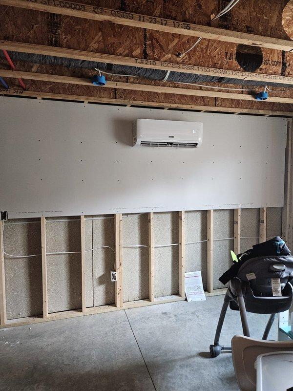 Completed installation of multi-zone ductless mini-split system including two outdoor condensing units mounted on prepared rock bed with proper drainage and electrical connections. Installed indoor wall-mounted air handler unit in interior space with refrigerant line sets, condensate drainage, and electrical wiring routed through building structure. System tested and verified operational upon completion.