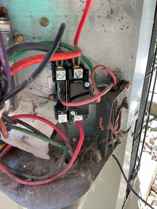# Air Conditioning No-Start Diagnostic

Responded to service call for 16-year-old air conditioning system that would not start or kick on. Upon arrival, performed comprehensive diagnostic evaluation of outdoor condensing unit and electrical components.

Inspection revealed extensive dirt, debris, and organic material accumulation throughout the electrical connection areas, including terminal blocks, contactors, and wiring compartments. Heavy soiling was observed on brass terminal connections with multiple colored control wires (red, green, black, pink, purple) showing disorganized routing and loose bundling. The outdoor unit displayed significant weathering and environmental exposure effects, with debris buildup around the base and mounting surfaces.

Examined electrical contactor assembly and found heavy contamination affecting electrical connections. Terminal block showed thick layer of dust and grime accumulation that had built up over extended period without regular maintenance. Al
