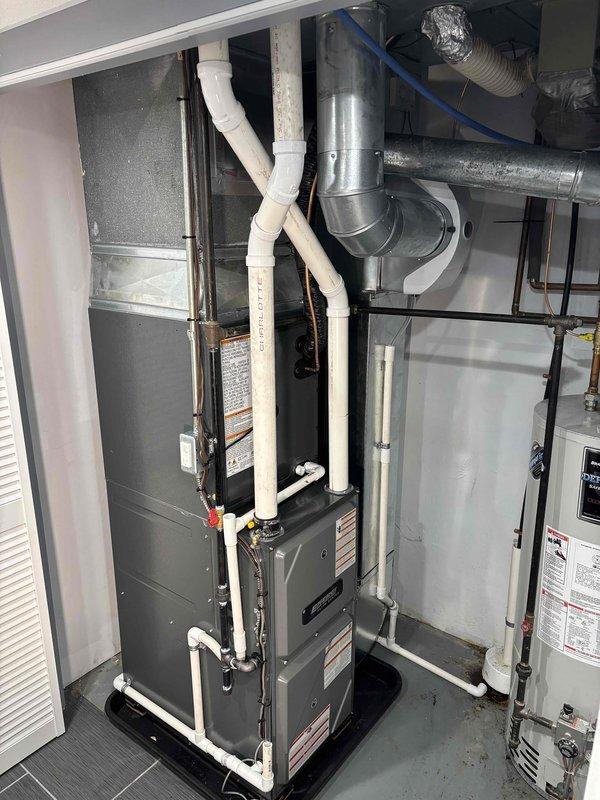 Completed full HVAC system installation including new Daikin furnace and air conditioning unit in residential mechanical room. Installed dark gray furnace unit with complete PVC condensate drainage and venting system, connected galvanized supply and return ductwork with proper transitions and elbows, and integrated flexible ducting as needed. Verified all gas connections with brass fittings properly secured, confirmed electrical connections per manufacturer specifications, and ensured adequate clearance around water heater and all mechanical equipment for code compliance and future maintenance access. System tested and operational.