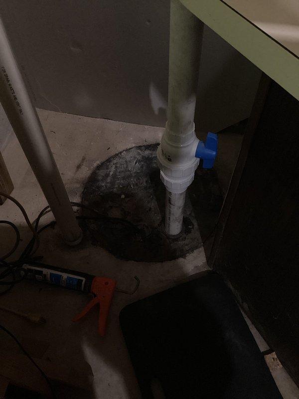 Responded to emergency service call for non-operational sump pump with reported sewage odor and slow-draining lower level toilet. Upon inspection, found sump pump basin with PVC discharge piping and confirmed pump failure. Assessed mechanical room conditions and identified moisture accumulation around pit area indicating drainage issues. Inspected affected bathroom fixture and verified sluggish flush performance consistent with potential drainage obstruction or pump system malfunction. Documented equipment conditions including basin configuration, discharge piping with blue valve assembly, and surrounding utility area. Evaluated correlation between non-functioning sump pump and compromised toilet drainage, determining pump failure was impacting overall lower level plumbing system performance.