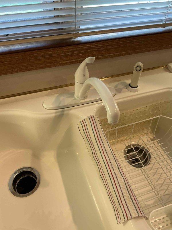 Responded to plumbing lead for leaking faucets at residential property. Inspected bathroom sink with chrome single-lever faucet and kitchen double-basin sink with single-handle faucet and spray attachment. Documented existing conditions of both fixtures to assess source of reported leaks and determine necessary repairs.