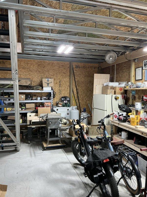 Conducted on-site evaluation of detached garage/workshop facility for new heating and cooling system installation. Assessed existing electrical infrastructure including main panel with adequate circuit capacity and properly installed conduit routing. Documented workspace layout including vehicle storage area, workbench configuration, and current ceiling-mounted ventilation equipment to determine optimal HVAC unit placement and ductwork routing considerations for climate control system installation.
