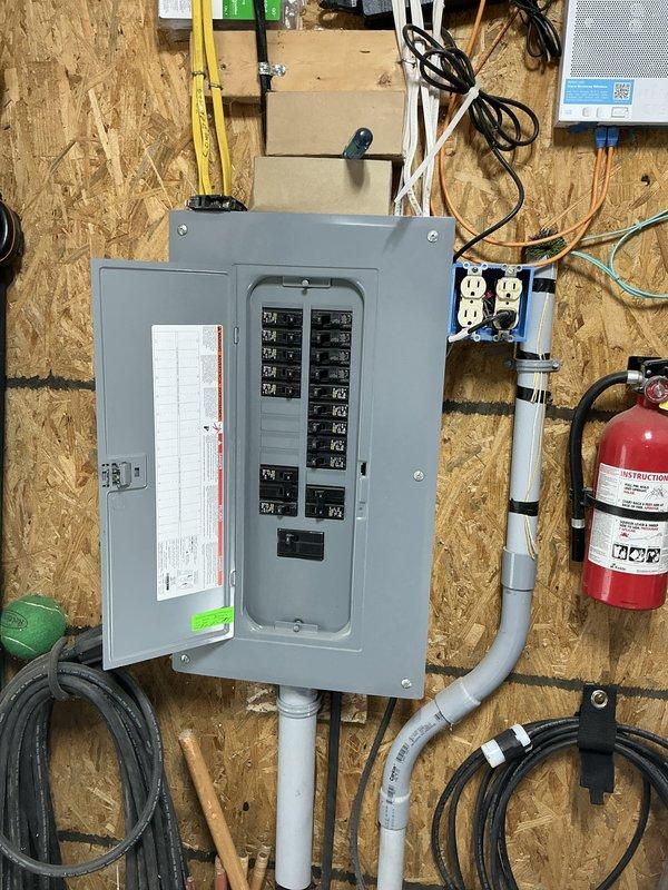Conducted on-site evaluation of detached garage/workshop facility for new heating and cooling system installation. Assessed existing electrical infrastructure including main panel with adequate circuit capacity and properly installed conduit routing. Documented workspace layout including vehicle storage area, workbench configuration, and current ceiling-mounted ventilation equipment to determine optimal HVAC unit placement and ductwork routing considerations for climate control system installation.