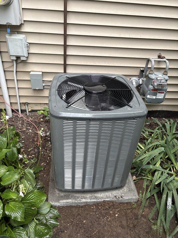 Completed full air conditioning system replacement at residential property. Removed existing outdoor condenser unit and installed new condensing unit on concrete pad against exterior wall near gas meter and electrical service panel. Unit positioned with proper clearances from foundation and landscaping. Interior work included installation of new evaporator coil in basement mechanical space with connections to existing ductwork system. Ran refrigerant lines, established proper refrigerant charge, and verified system pressures. Connected electrical service, tested all safety controls, and confirmed proper airflow throughout system. System commissioned and operating within manufacturer specifications upon completion.