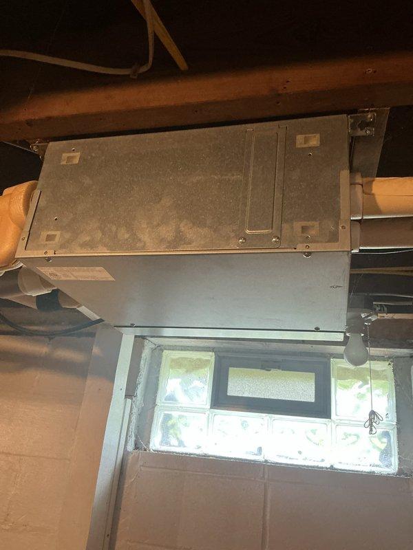 Responded to no cooling complaint on four Fujitsu mini-split units approximately 10 years old. Inspected air handler located in attic space and found evidence of refrigerant leak in upstairs bedroom unit. Photographed dusty air handler mounted near attic window and basement-mounted equipment with visible PVC condensate lines and ductwork. System requires refrigerant leak repair and recharge to restore cooling capacity to all four zones.