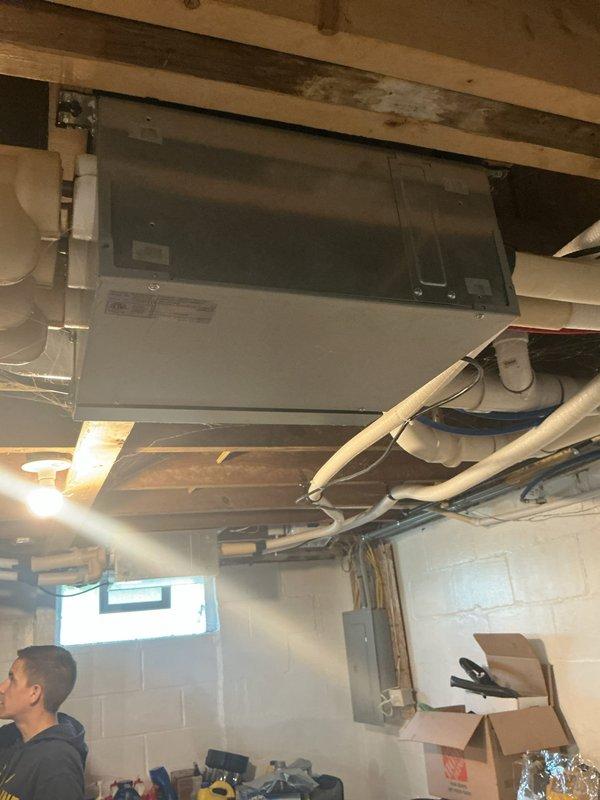 Responded to no cooling complaint on four Fujitsu mini-split units approximately 10 years old. Inspected air handler located in attic space and found evidence of refrigerant leak in upstairs bedroom unit. Photographed dusty air handler mounted near attic window and basement-mounted equipment with visible PVC condensate lines and ductwork. System requires refrigerant leak repair and recharge to restore cooling capacity to all four zones.
