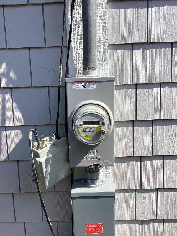 Conducted on-site assessment for generator installation at single-family residence with no existing backup power system. Evaluated existing electrical service infrastructure, including main meter assembly with Milbank equipment and service panel mounted on exterior gray shake siding. Documented current electrical configuration with multiple conduit runs along building exterior and assessed available space for generator placement and associated transfer switch installation. Photographed electrical service entrance, meter base, disconnect boxes, and building exterior to determine optimal equipment location and electrical tie-in requirements for proposed automatic standby generator system.