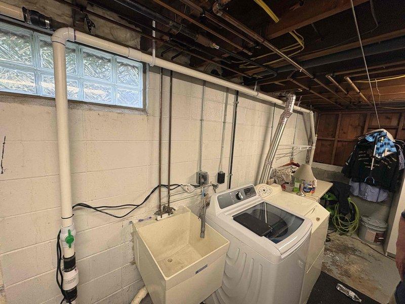 Completed installation of new sump pump system in basement utility area. Installed pump unit with cover, ran electrical connections along wall to power source, and verified proper operation of discharge system to protect laundry area from water intrusion.