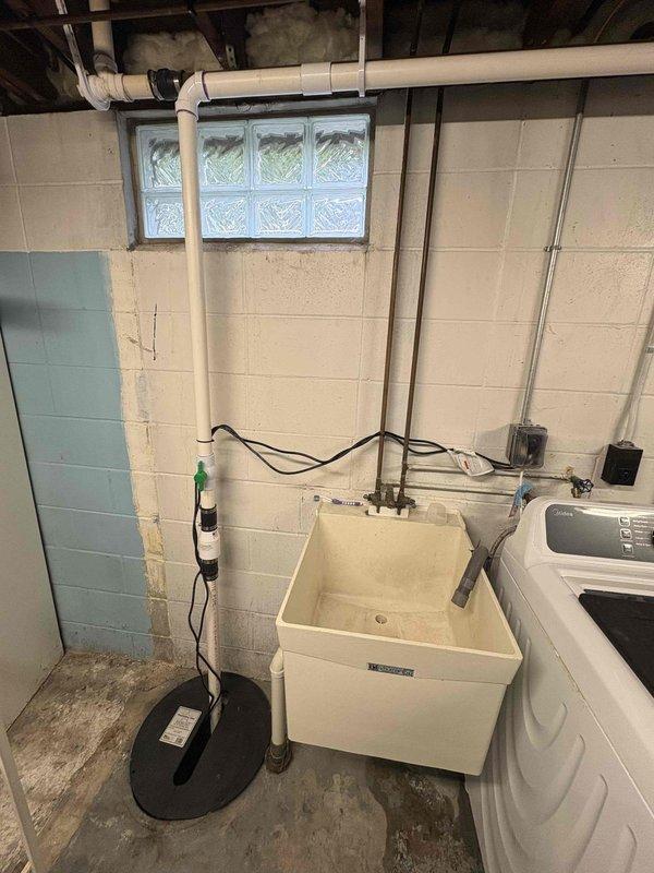 Completed installation of new sump pump system in basement utility area. Installed pump unit with cover, ran electrical connections along wall to power source, and verified proper operation of discharge system to protect laundry area from water intrusion.