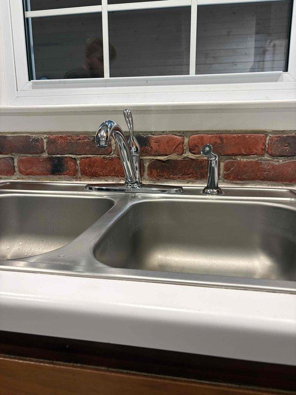 Responded to kitchen faucet service call for malfunctioning spray nozzle that was continuously spraying and leaking. Diagnosed faulty spray head diverter valve causing constant water flow through the side sprayer. Replaced defective spray nozzle assembly and tested operation to confirm proper function. Verified all connections under sink were secure and no additional leaks were present in the supply lines or P-trap drainage system.