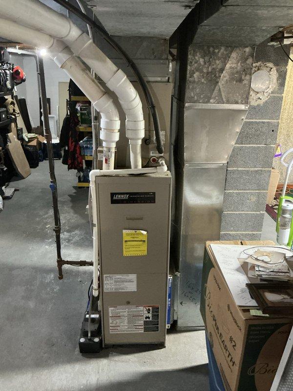 Conducted comprehensive sales estimate for replacement of 16-year-old furnace and air conditioning system in residential basement location. Documented existing Lennox furnace installation, including current ductwork configuration, gas line connections with yellow flexible supply line and black pipe fittings, and PVC venting system. Photographed equipment condition, surrounding infrastructure including concrete block foundation walls, structural support beams, and utility area layout to assess installation requirements and access considerations for future system replacement.