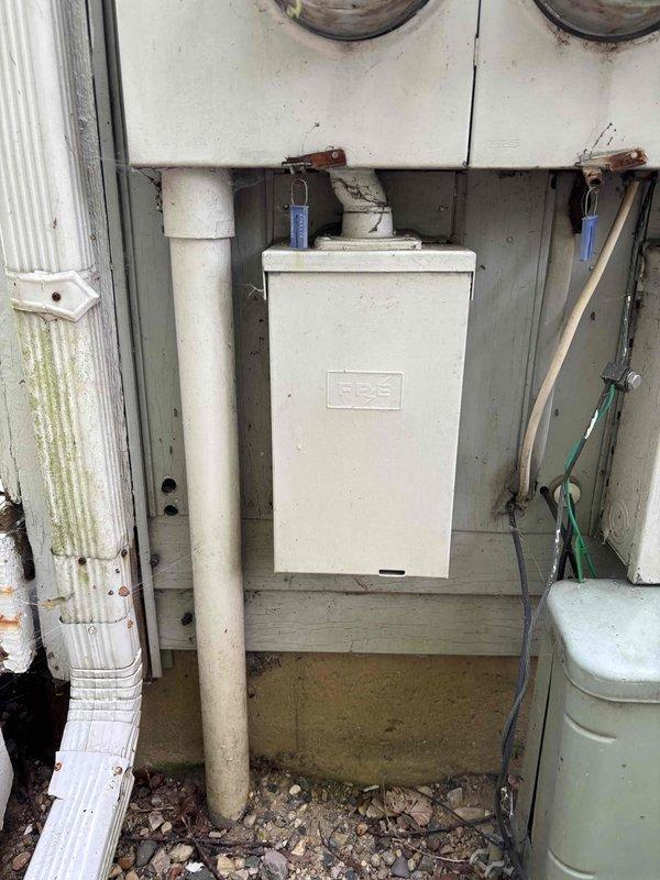 Conducted comprehensive electrical panel assessment for 46-year-old residential condo unit requiring full panel replacement due to discontinued equipment with known fire hazard risks. Evaluated existing outdoor utility installation featuring white metal IPES electrical panel mounted on exterior wall with multiple meter configuration serving the property. Documented current electrical infrastructure including four-meter bank installation, existing conduit routing, panel mounting conditions, and associated utility connections. Assessed weathered exterior components, panel accessibility, grounding systems, and service entry configuration to determine scope of complete panel replacement required to bring system up to current safety standards and code compliance.