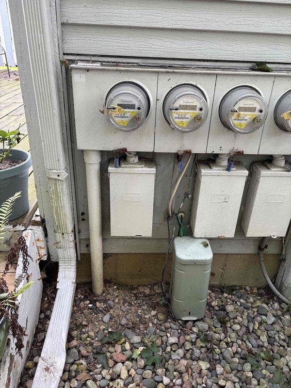 Conducted comprehensive electrical panel assessment for 46-year-old residential condo unit requiring full panel replacement due to discontinued equipment with known fire hazard risks. Evaluated existing outdoor utility installation featuring white metal IPES electrical panel mounted on exterior wall with multiple meter configuration serving the property. Documented current electrical infrastructure including four-meter bank installation, existing conduit routing, panel mounting conditions, and associated utility connections. Assessed weathered exterior components, panel accessibility, grounding systems, and service entry configuration to determine scope of complete panel replacement required to bring system up to current safety standards and code compliance.