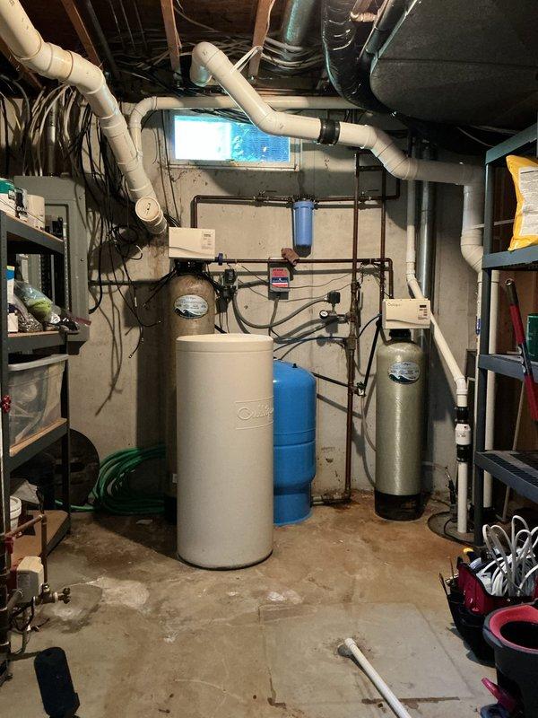 Completed estimate for whole-home water heater replacement and water softener system upgrade in a 30-year-old residence. Assessed existing A.O. Smith water heater, water softener with control head, pressure tank, and associated plumbing infrastructure in basement utility area. Provided recommendations for modernizing the complete water treatment and heating system to improve efficiency and performance.