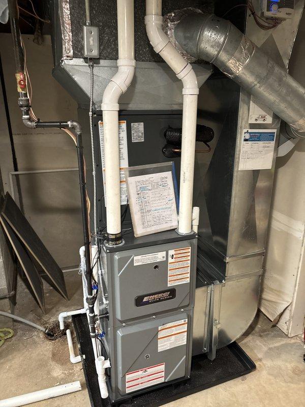 Completed full HVAC system installation including new high-efficiency furnace with PVC intake and exhaust venting in basement utility area, mounted on protective base pad with proper clearances. Installed ductwork connections with reflective insulation and flexible ducting, completed electrical conduit work and wiring. Added outdoor mini-split condenser unit on concrete pad against exterior wall with black line set run through wall penetration, secured with mounting bracket. Verified all components operational, system tested and commissioned successfully.