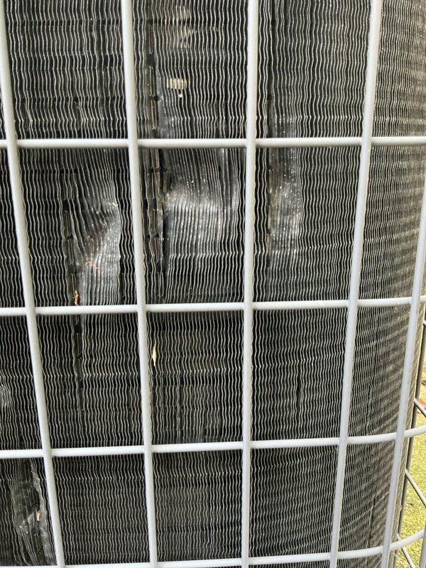 Completed annual cooling maintenance on approximately 20-year-old air conditioning system. Inspected condenser unit and found significant debris accumulation on coil fins requiring attention. Documented equipment condition including motor assembly, electrical connections, and overall system components for maintenance records.