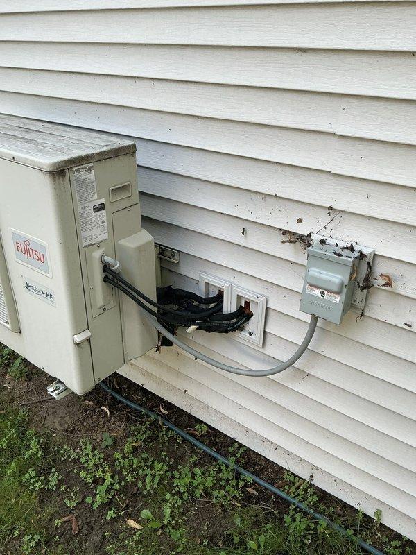 Conducted estimate for mini-split system evaluation at residential property. Assessed existing Fujitsu outdoor condenser unit mounted on exterior wall with visible wear to surrounding siding and electrical disconnect box area. Evaluated electrical panel capacity and configuration in unfinished interior space to determine compatibility for potential system upgrades or modifications, noting current breaker arrangement and available capacity for additional HVAC equipment installation.