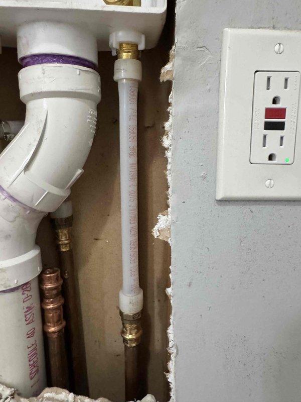 Completed laundry box repair involving exposed plumbing installation within wall cavity. Accessed and repaired connections between white PVC drainage pipes and copper water supply lines, including elbow joint fittings and flexible supply lines with brass compression fittings. Verified GFCI outlet functionality and secured all plumbing connections within the wall structure. Work completed within the quoted 3-hour timeframe with customer waiting on-site.
