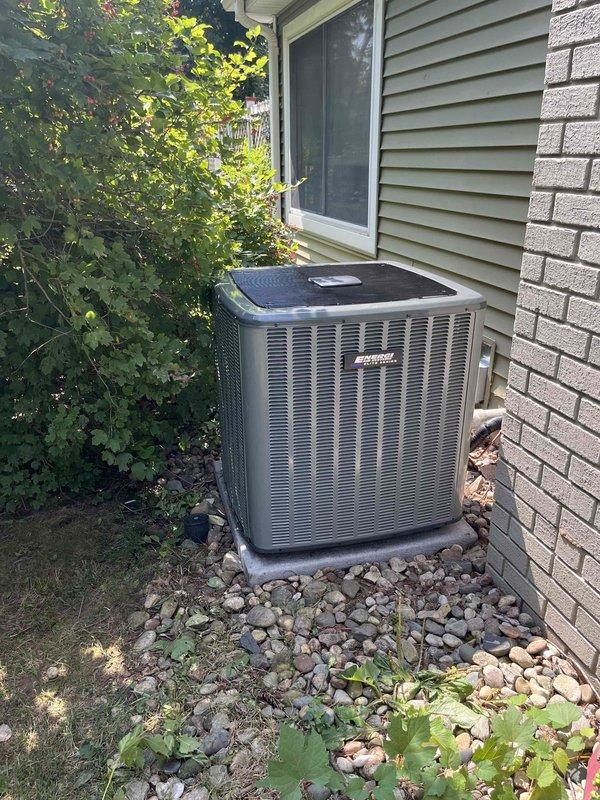 Completed full HVAC system installation including new furnace and air conditioning condenser unit. Furnace installed in basement utility area with proper ductwork integration, PVC venting, and condensate drainage system on protective drain pan. Outdoor AC condenser unit positioned on concrete pad with landscaping rock bed, electrical disconnect box mounted, and all refrigerant lines connected and tested for proper operation.