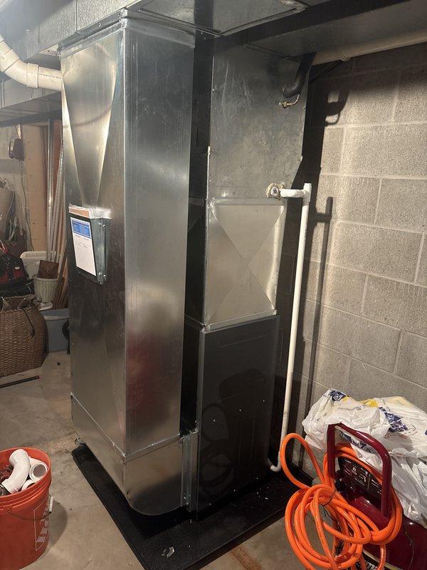 Completed full furnace installation in basement utility area. Installed new Amana gas furnace unit on protective base pad with proper venting system including PVC exhaust pipes and ductwork connections. Connected gas line, electrical conduit, and silver supply/return ductwork to ensure complete system integration and proper airflow throughout the residence.
